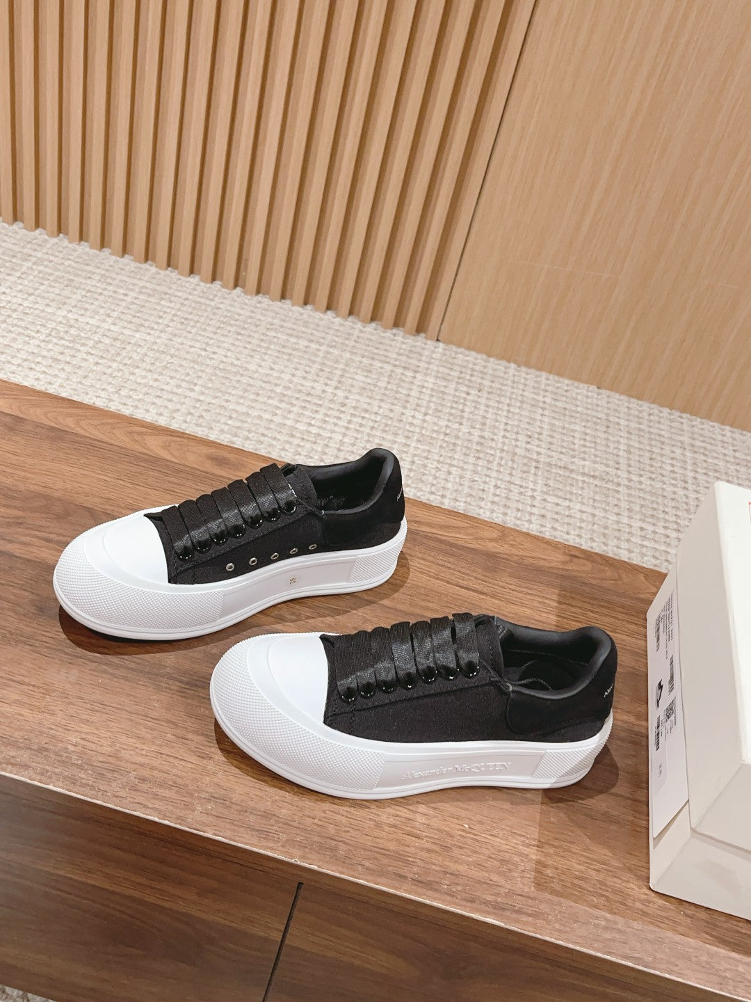 Black low-top sneakers with white rubber sole and studded textured panel across side