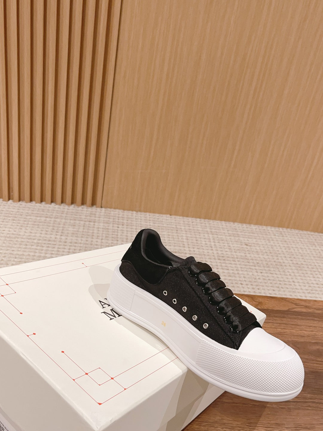 Black lace-up sneaker with white rubber sole and small metal eyelet accents