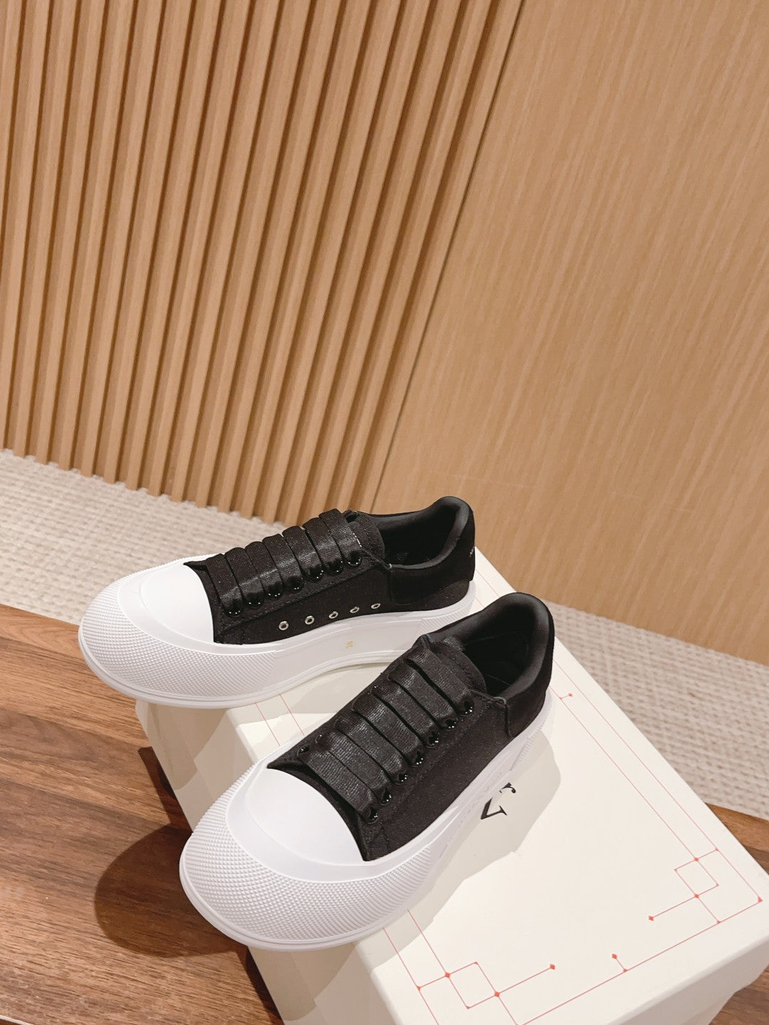 Black slip-on sneakers with white soles, studded strap detail across upper
