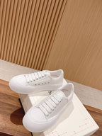 White lace-up sneakers with textured sidewall and stitched upper panels