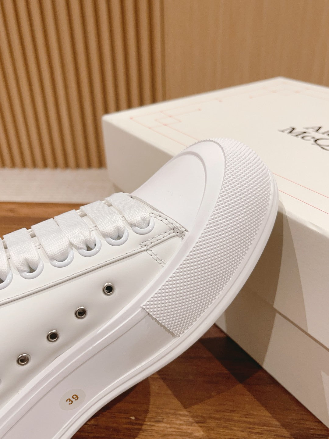 Close-up of white sneaker side with textured rubber sole edge and metal eyelets