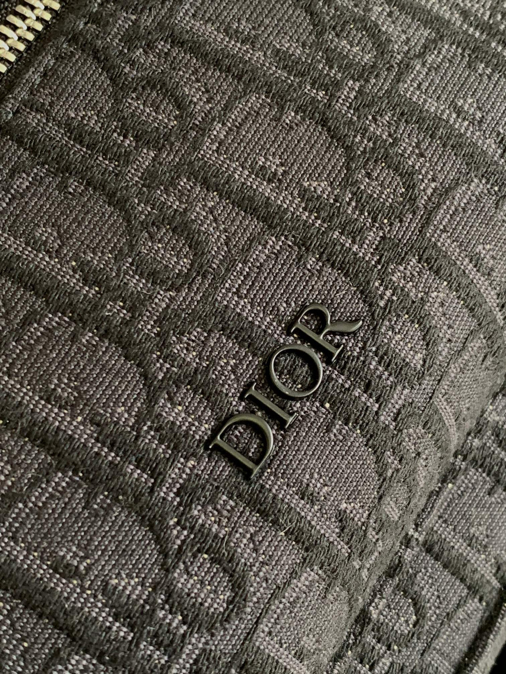 Dior logo metal snap detail on textured monogram fabric, dark