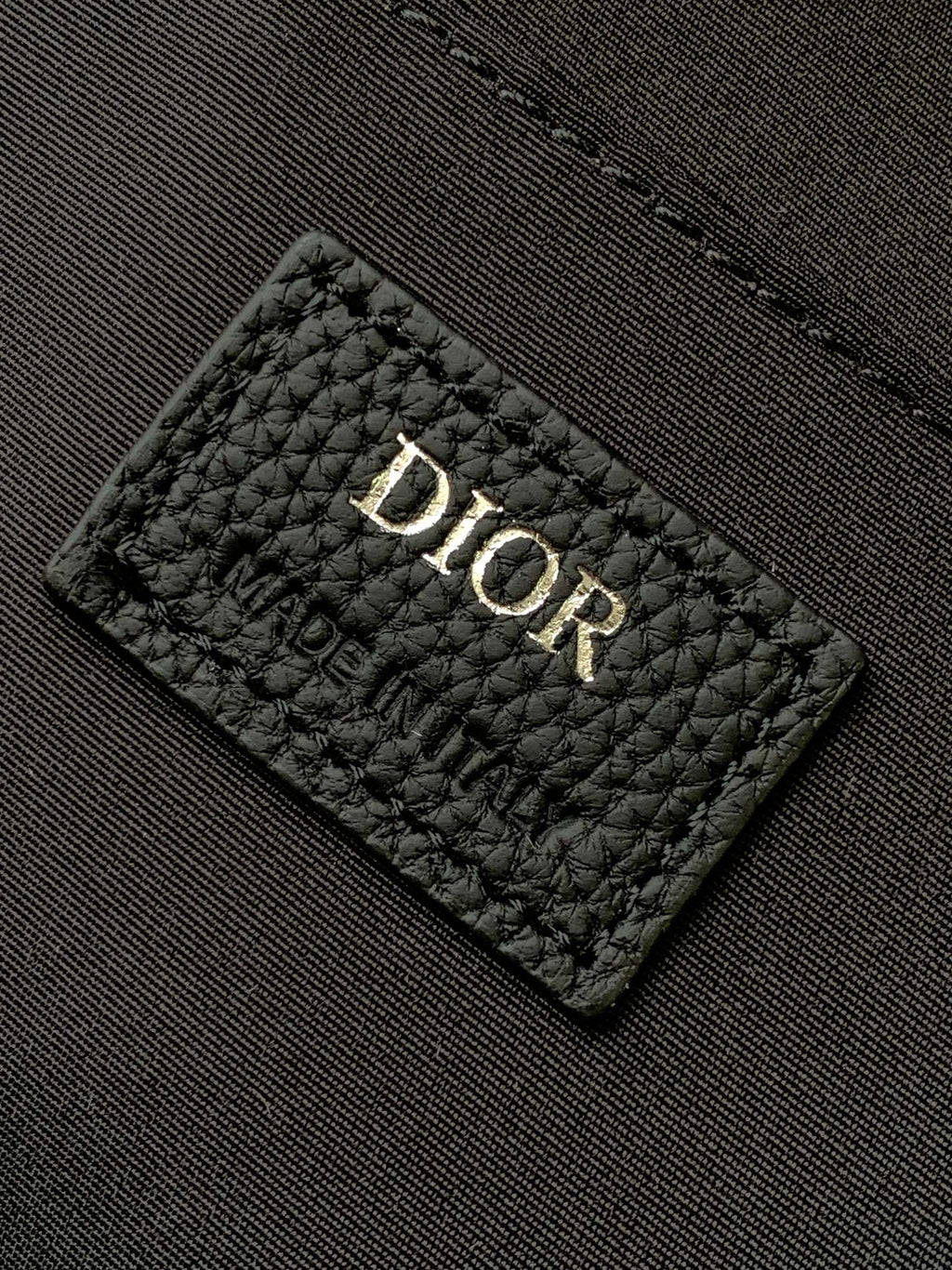 Dior quilted label patch with "Dior" text on the backpack lining