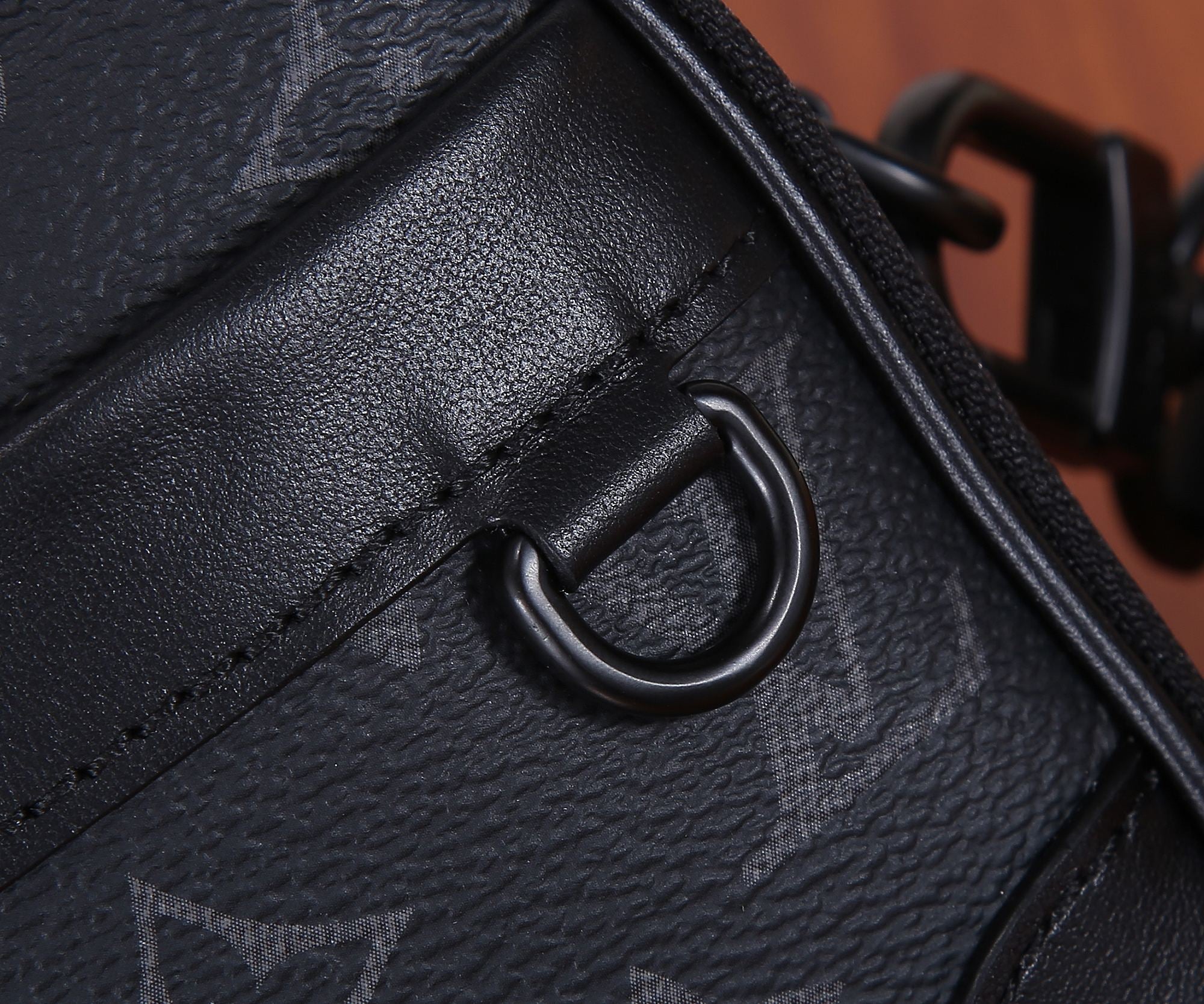 Louis Vuitton monogram bag strap attachment ring with black hardware, close-up