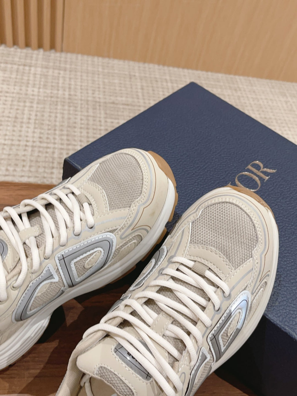Dior unisex sneakers side view with gray logo and white laces, light beige upper