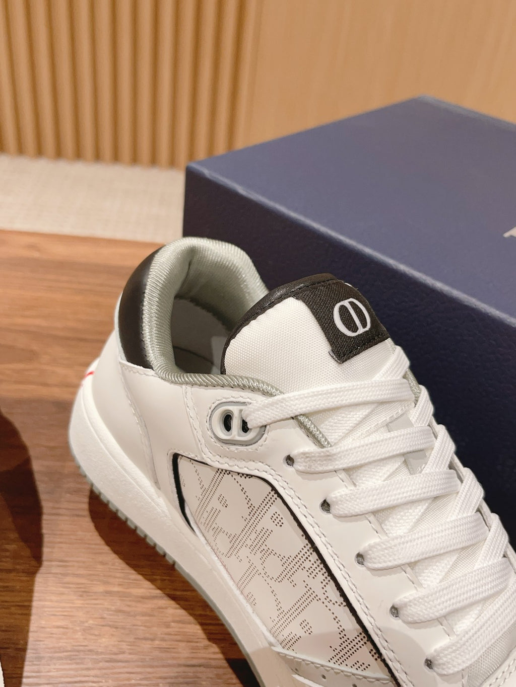 Dior unisex luxury shoes, close-up of white sneaker with black panel and lace-up
