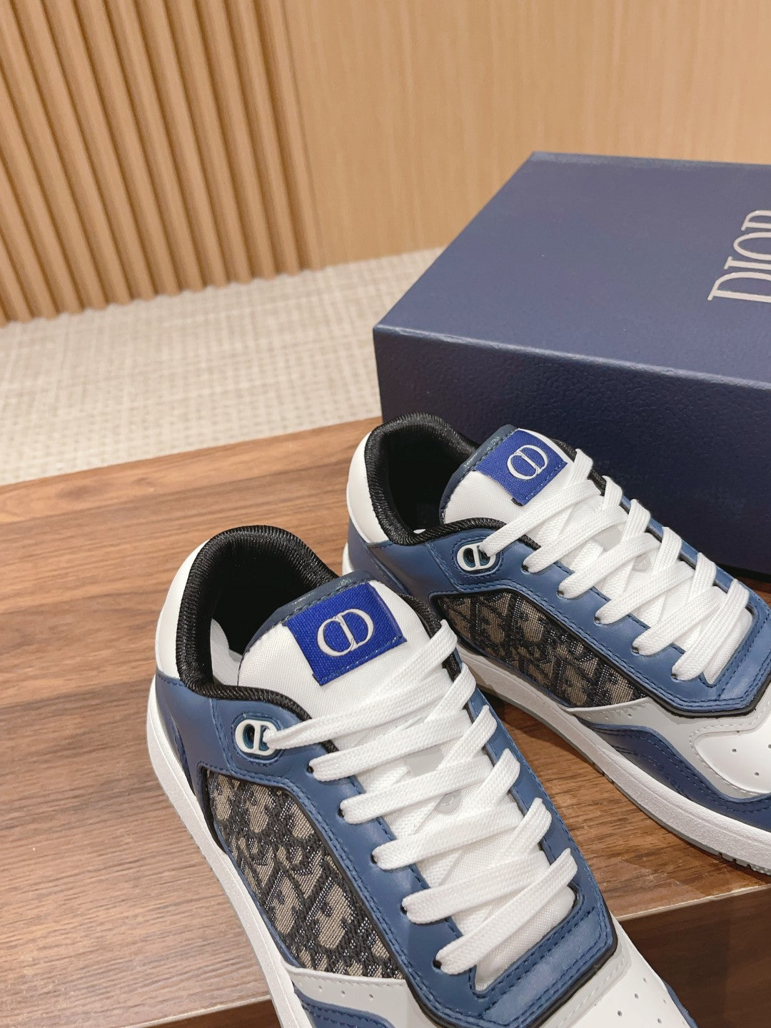 Unisex low-top sneakers with white laces, blue accents, and Dior logo on tongue