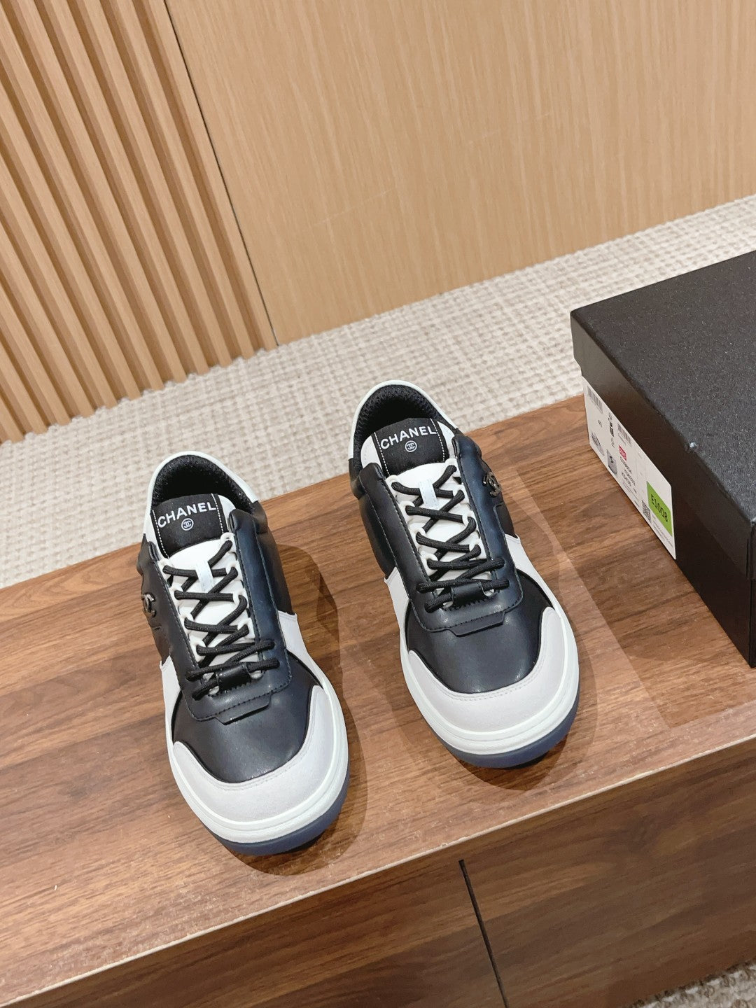 Black and white lace-up sneakers with white rubber sole and Chanel logo patch