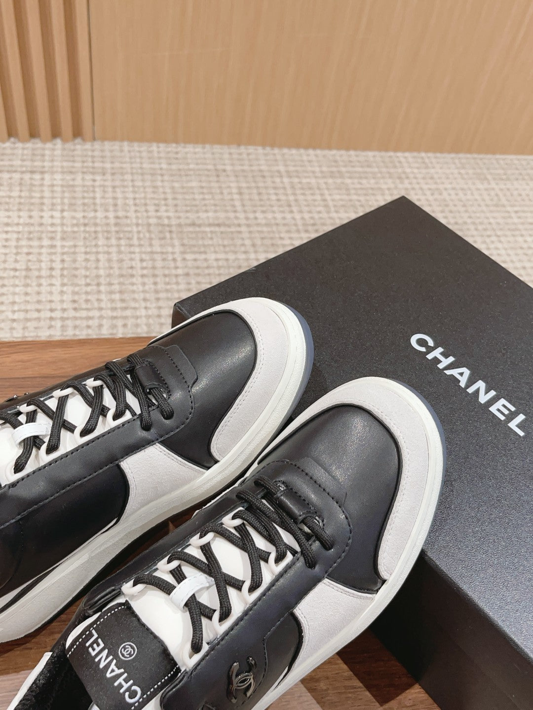 Close-up black sneakers with white laces, white sole, and Chanel logo on tongue