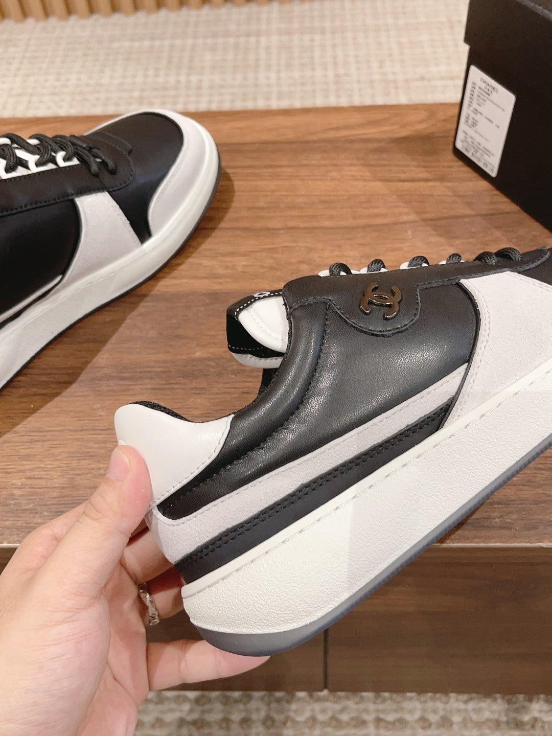 Black and white sneaker with gold emblem on side and grippy white sole