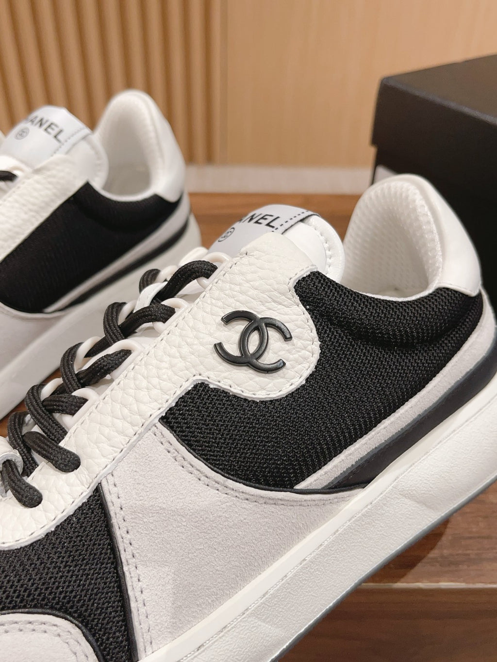 Unisex sneaker close-up, black and white leather with side emblem and laces
