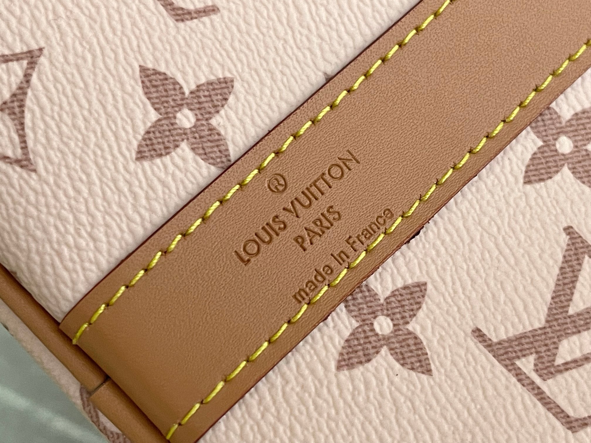 Beige leather tag on Louis Vuitton bag with embossed 'Louis Vuitton Paris' text