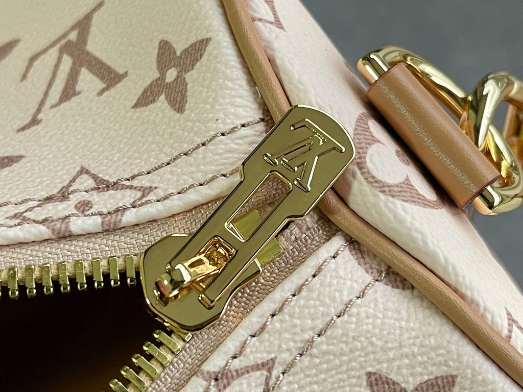 Zipper pull and clasp on beige monogram bag with tan leather trim