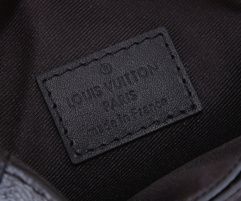 Louis Vuitton brand label patch on the interior of a dark monogram bag.