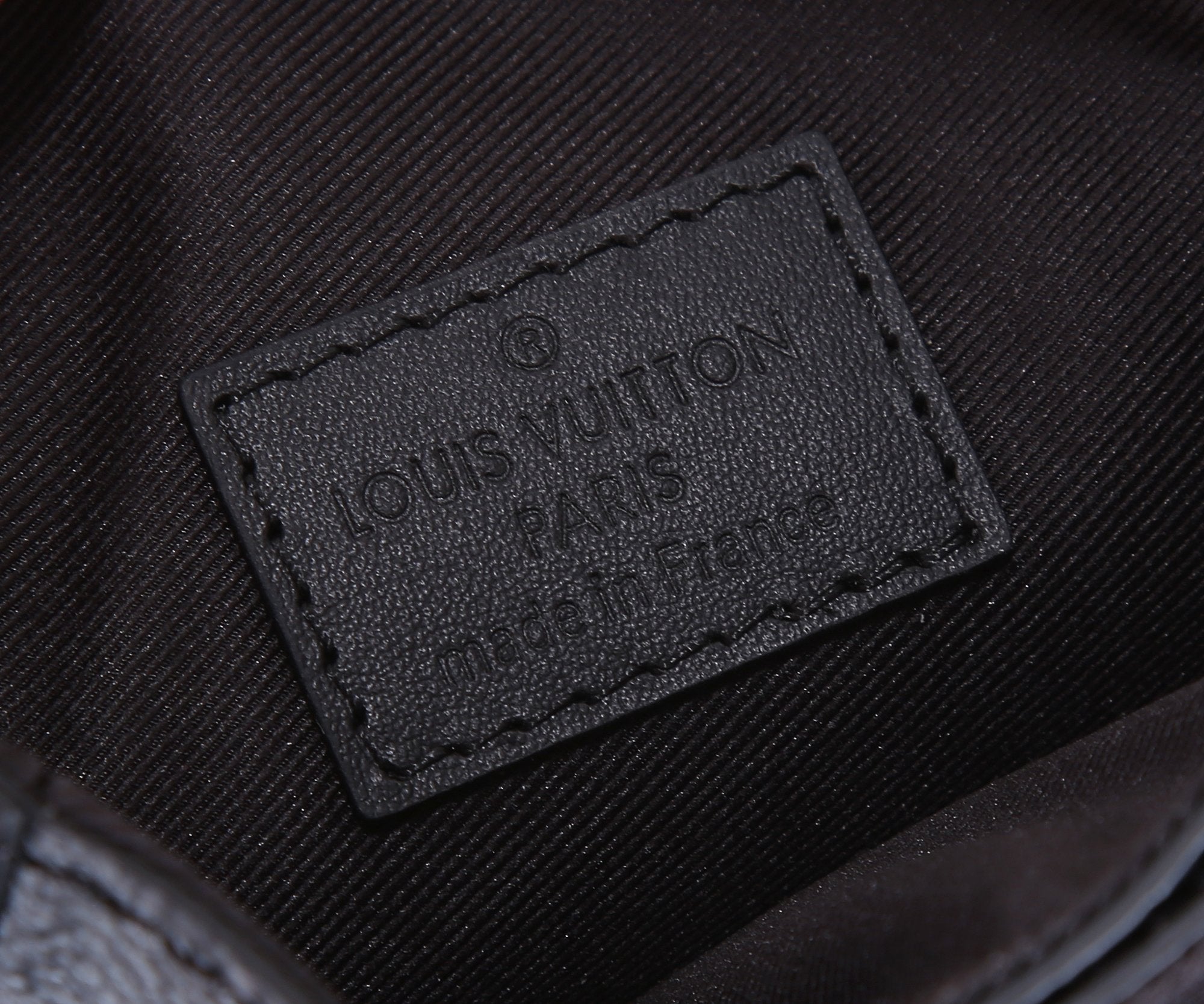 Louis Vuitton bag interior label patch embossed on dark fabric lining