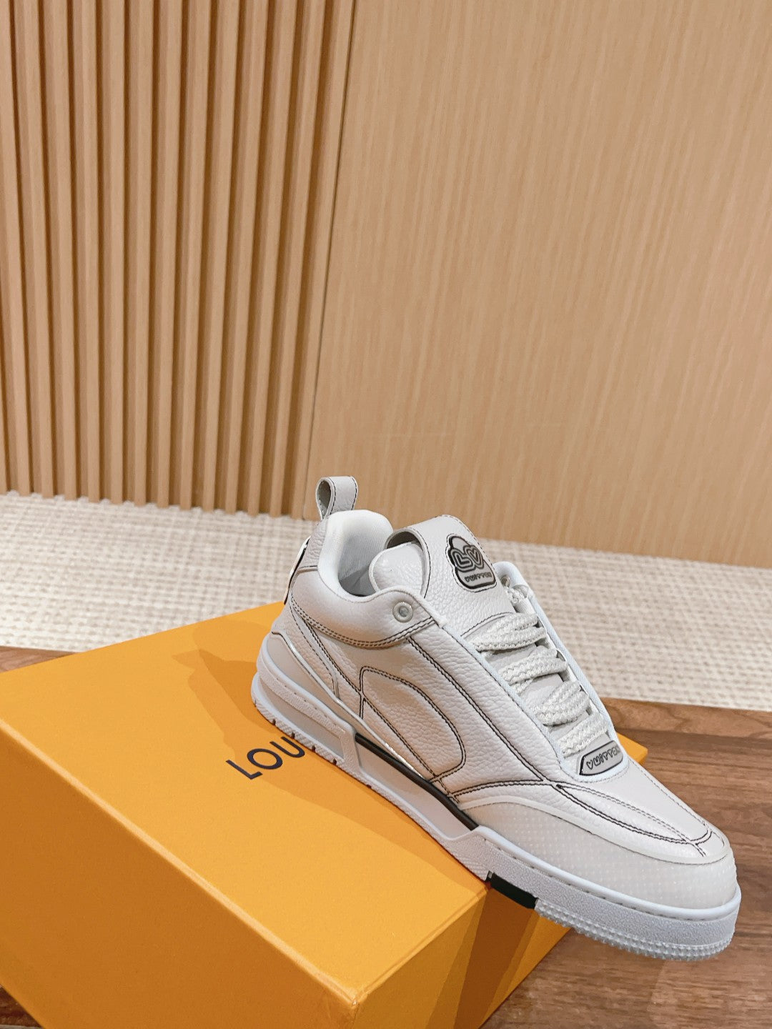 White Louis Vuitton leather sneakers, lace-up, side view with one shoe on box