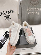 Pair of Chanel white sneakers with pink laces, thick sole, and sherpa-lined collar