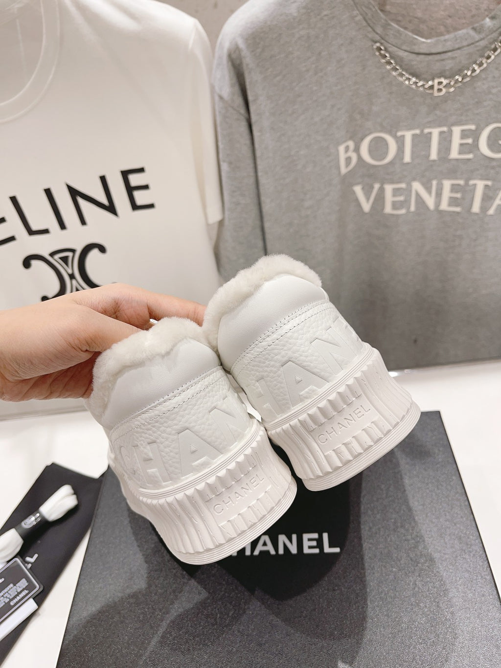 Chanel white sneakers displayed with textured rubber outsoles and sherpa-lined collars