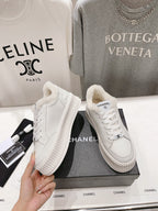 Pair of white lace-up sneakers with plush collar and ribbed platform sole