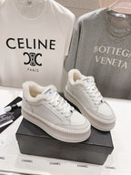 Two white lace-up sneakers with plush collars and textured platform soles