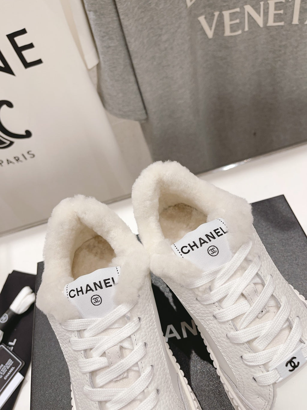Close-up of white sneakers: plush tongues, white laces, and ribbed platform soles