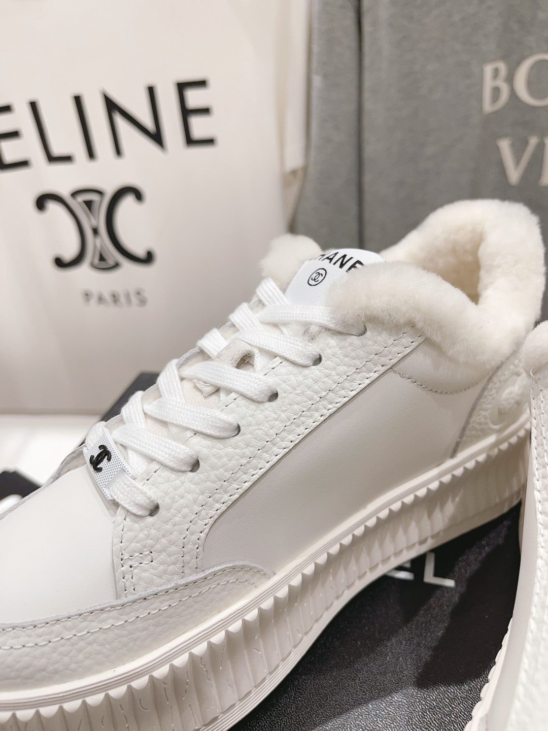 White lace-up sneaker with plush collar and side logo detail, angled view