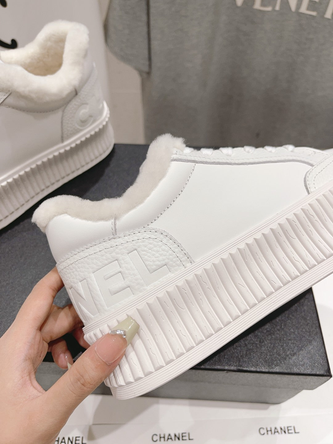 White sneaker with embossed side logo and ribbed platform sole, close-up