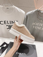 Women’s beige Chanel low-top sneakers with white laces and plush shearling trim