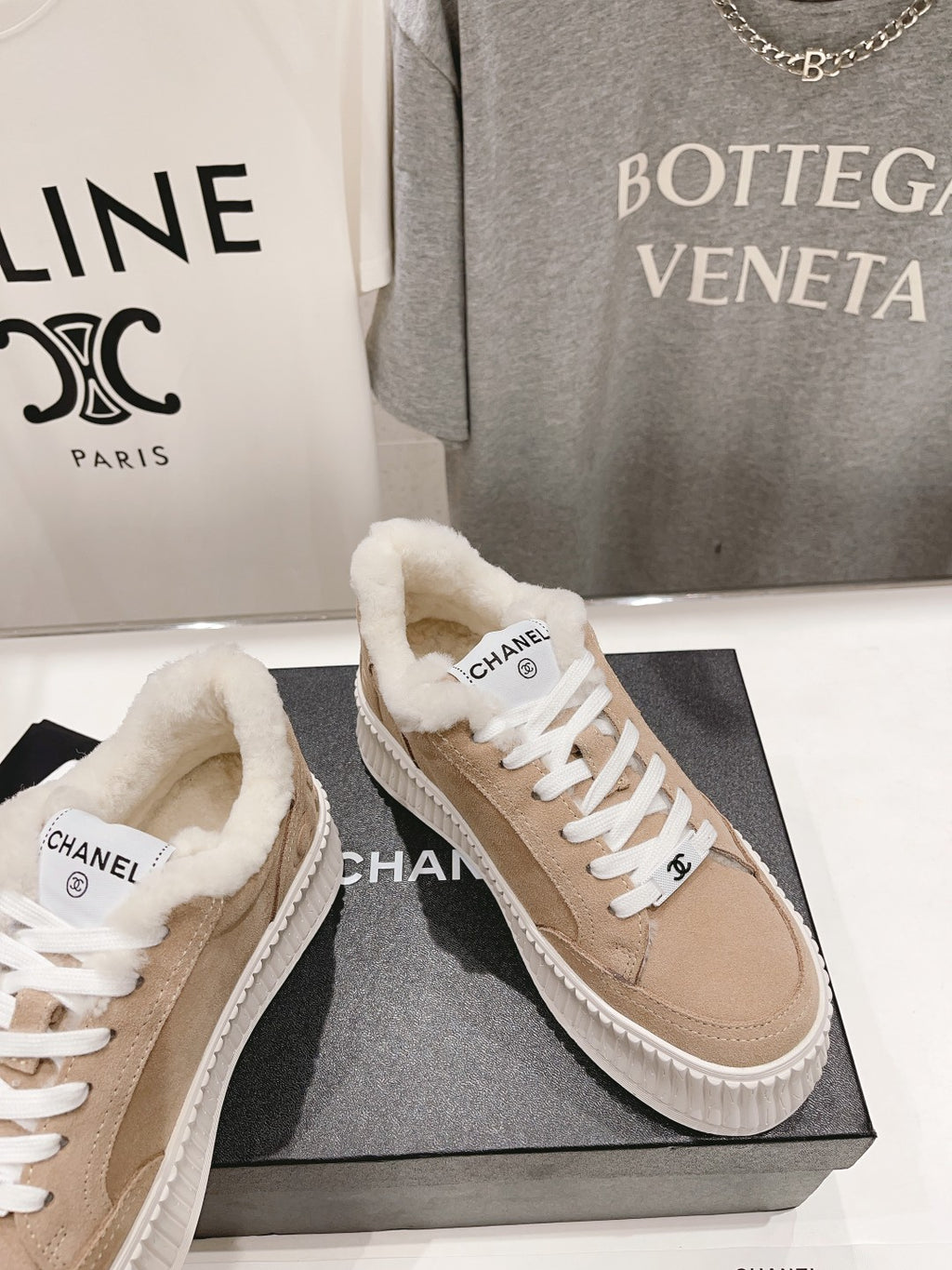Women’s beige Chanel sneakers with plush shearling collar and white lace-up front