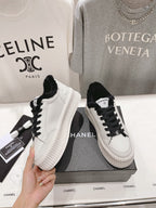 Women’s Chanel lace-up sneakers in white with black laces, plush collar, ribbed platform