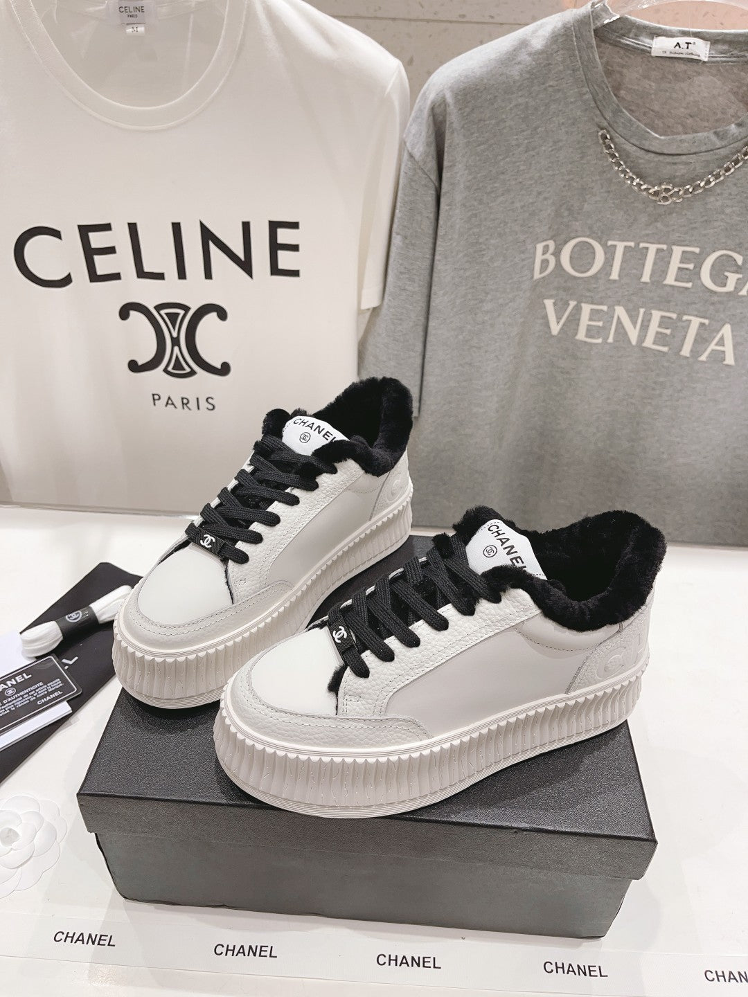 Women’s Chanel luxury sneakers, white with black laces and fuzzy collar on a shoebox