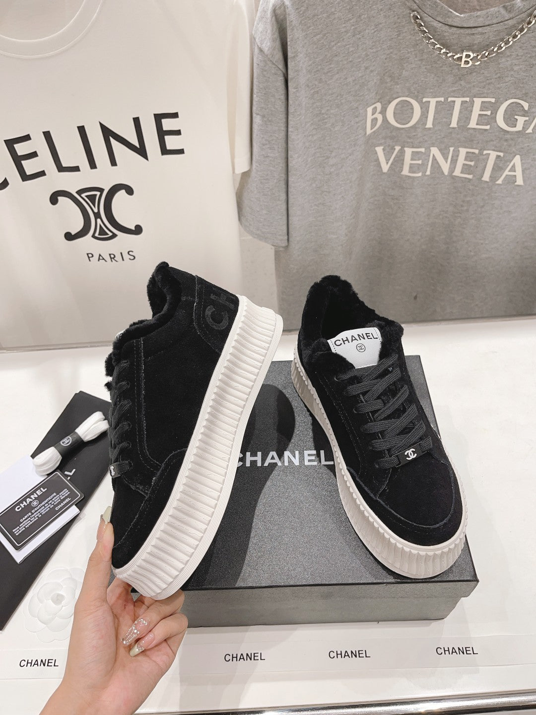 Black suede lace-up sneakers with white ridged sole and Chanel logo patch on tongue