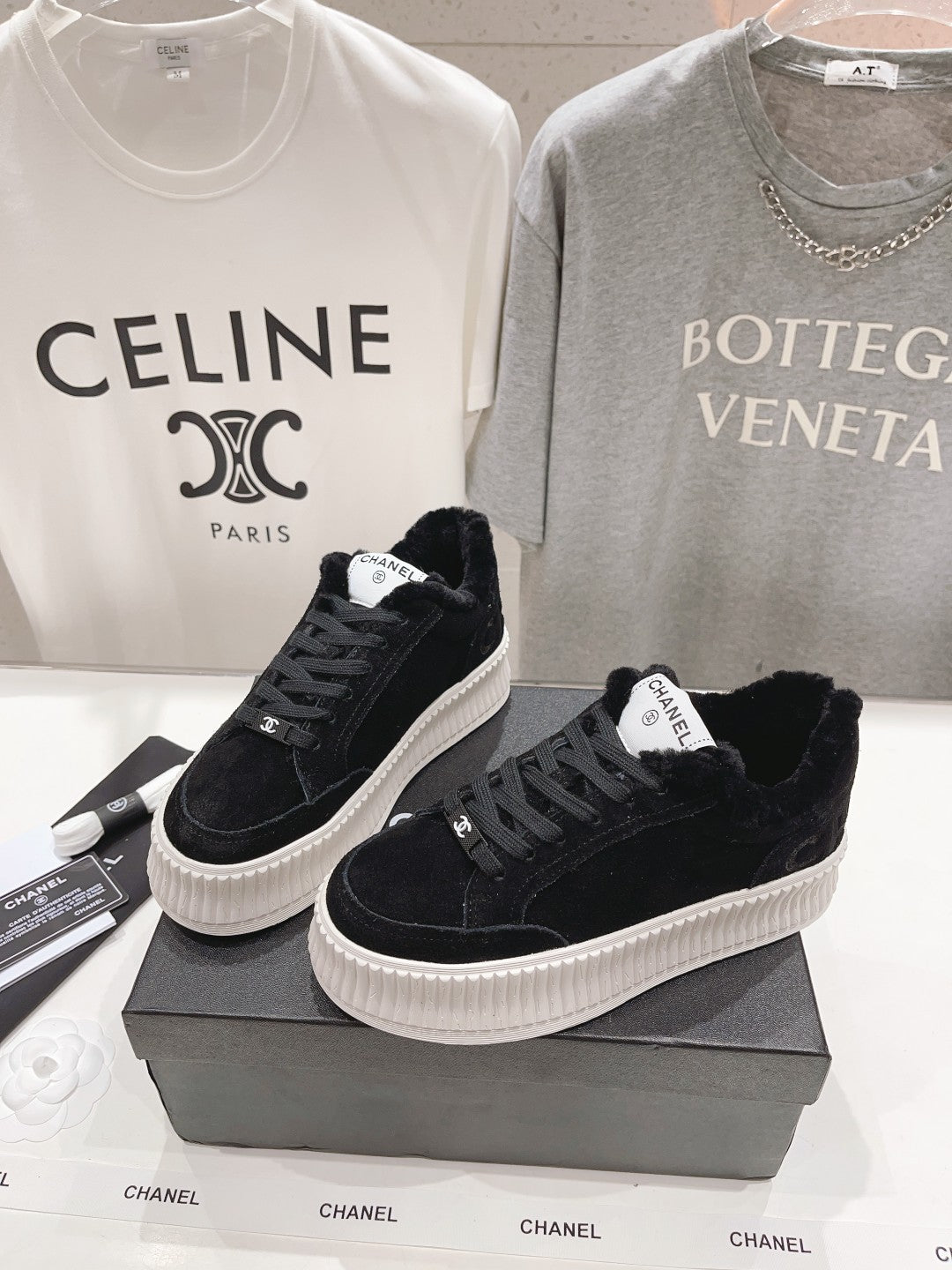 Pair of black lace-up sneakers with white ridged soles on black Chanel boxes