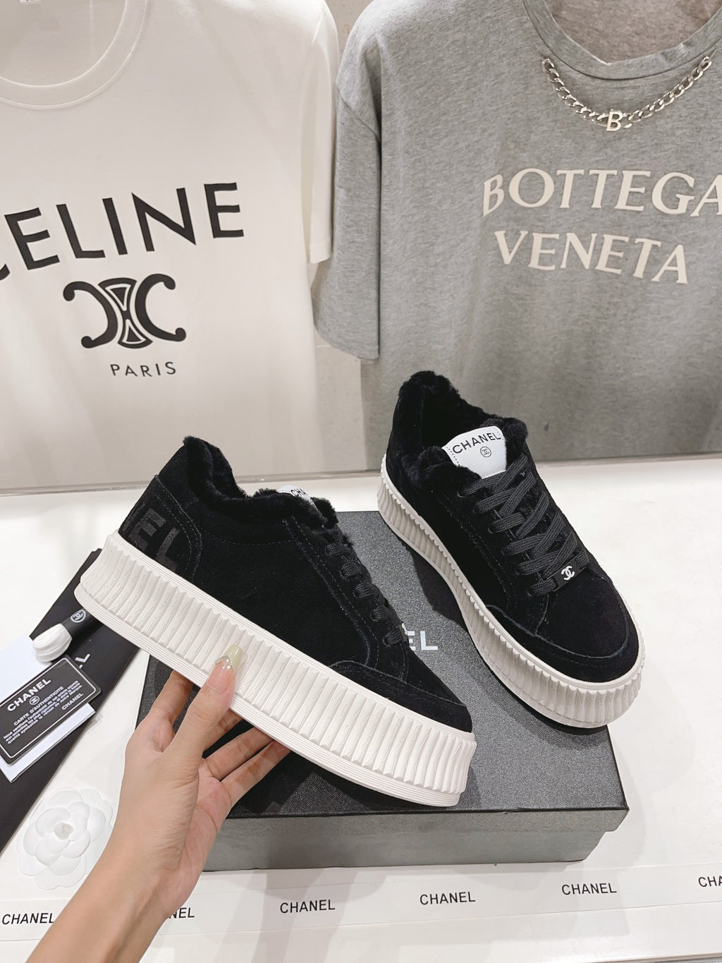 Black suede lace-up sneakers with white ridged soles and Chanel logo on side