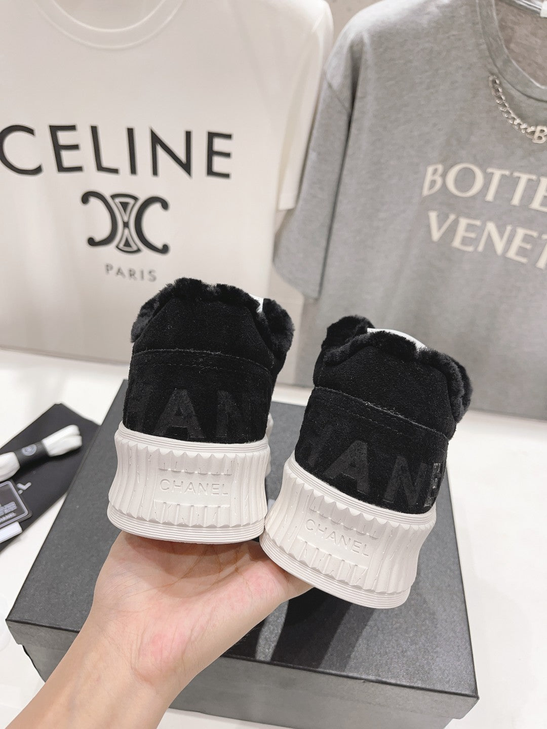 Back view of black lace-up sneakers with white ridged soles and Chanel branding on heel