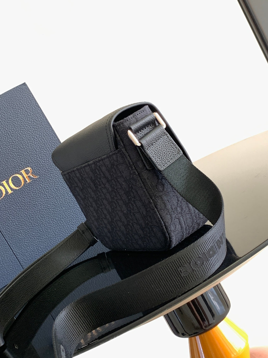Dior crossbody bag with flap buckle and adjustable strap, dark side view