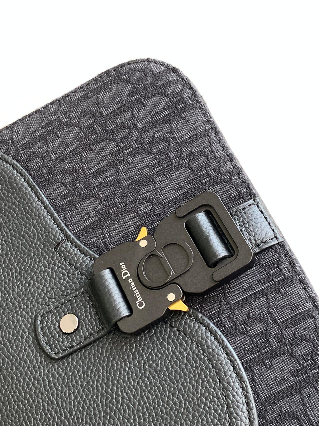 Dior crossbody bag hardware detail with logo plate and snap tab, textured leather