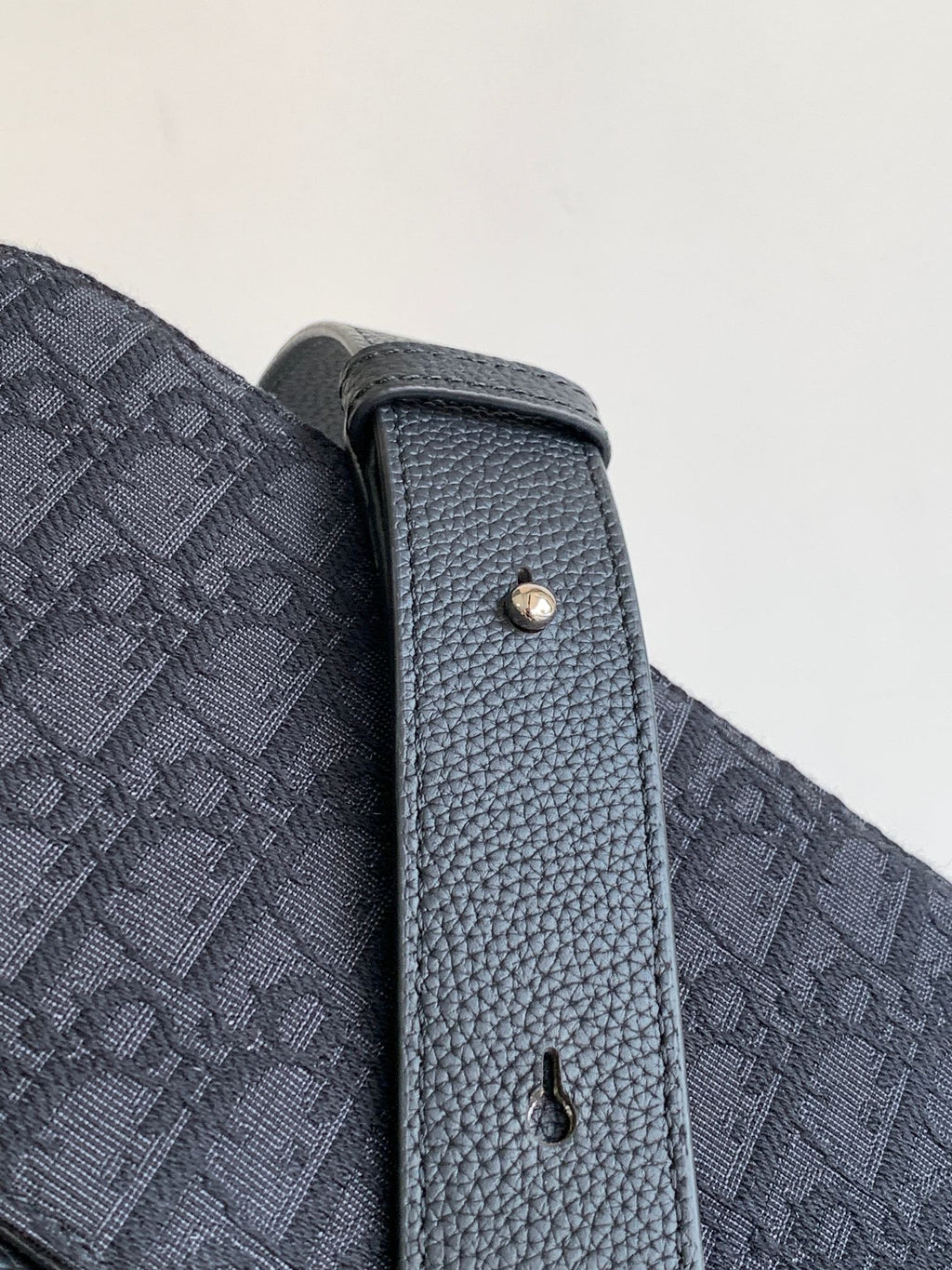 Dior crossbody bag side panel with textured leather edge and metal eyelet