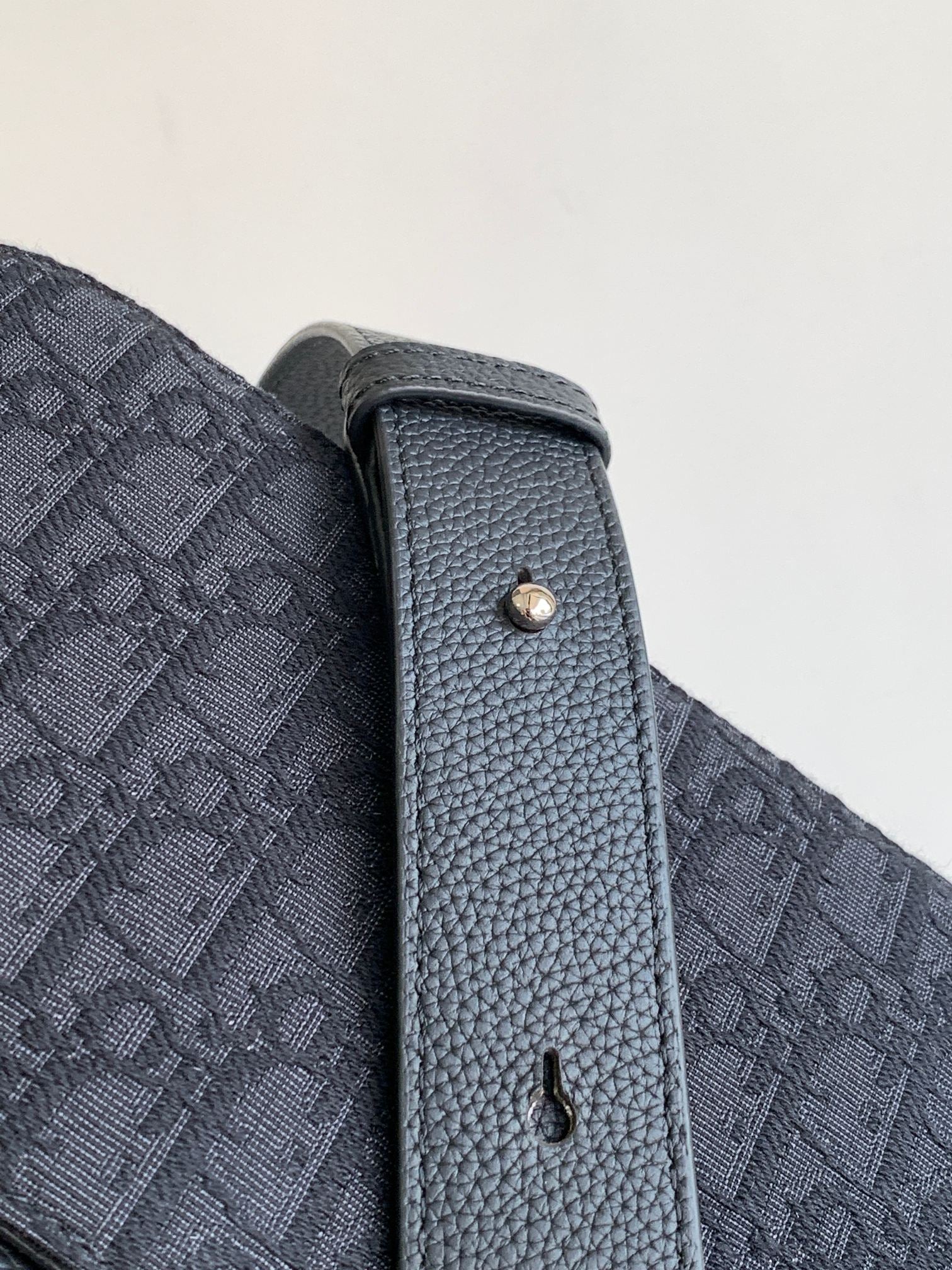 Dior crossbody bag side panel with textured leather edge and metal eyelet
