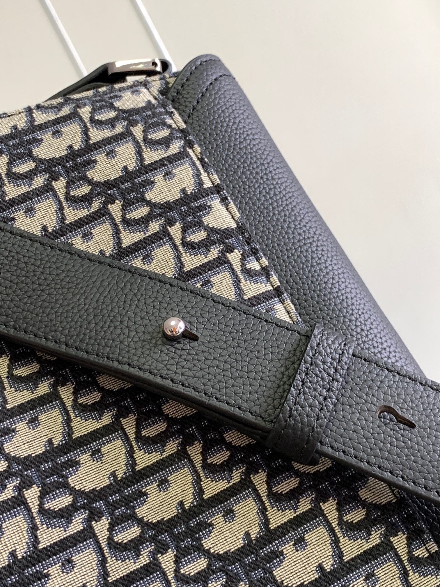 Dior bag close-up: black flap edge with Dior monogram canvas and metal toggle