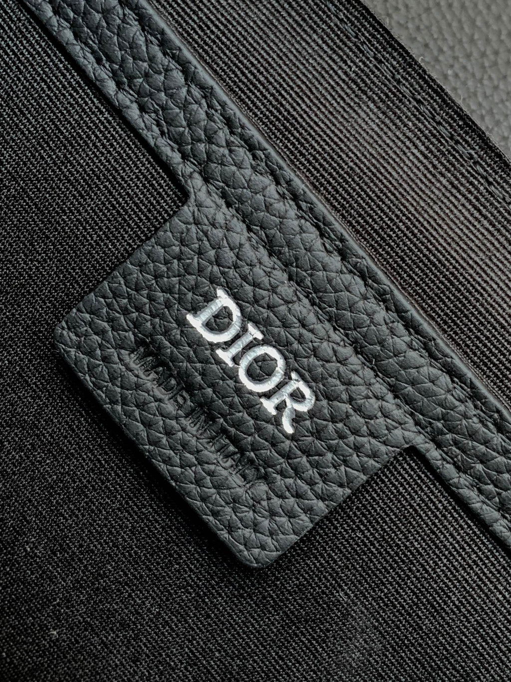Dior bag detail: Dior logo stamped on black textured leather card holder