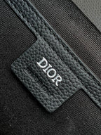 Dior bag detail: Dior logo stamped on black textured leather card holder