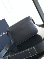 Dark textured leather crossbody bag with flap, buckles, and metal clasp
