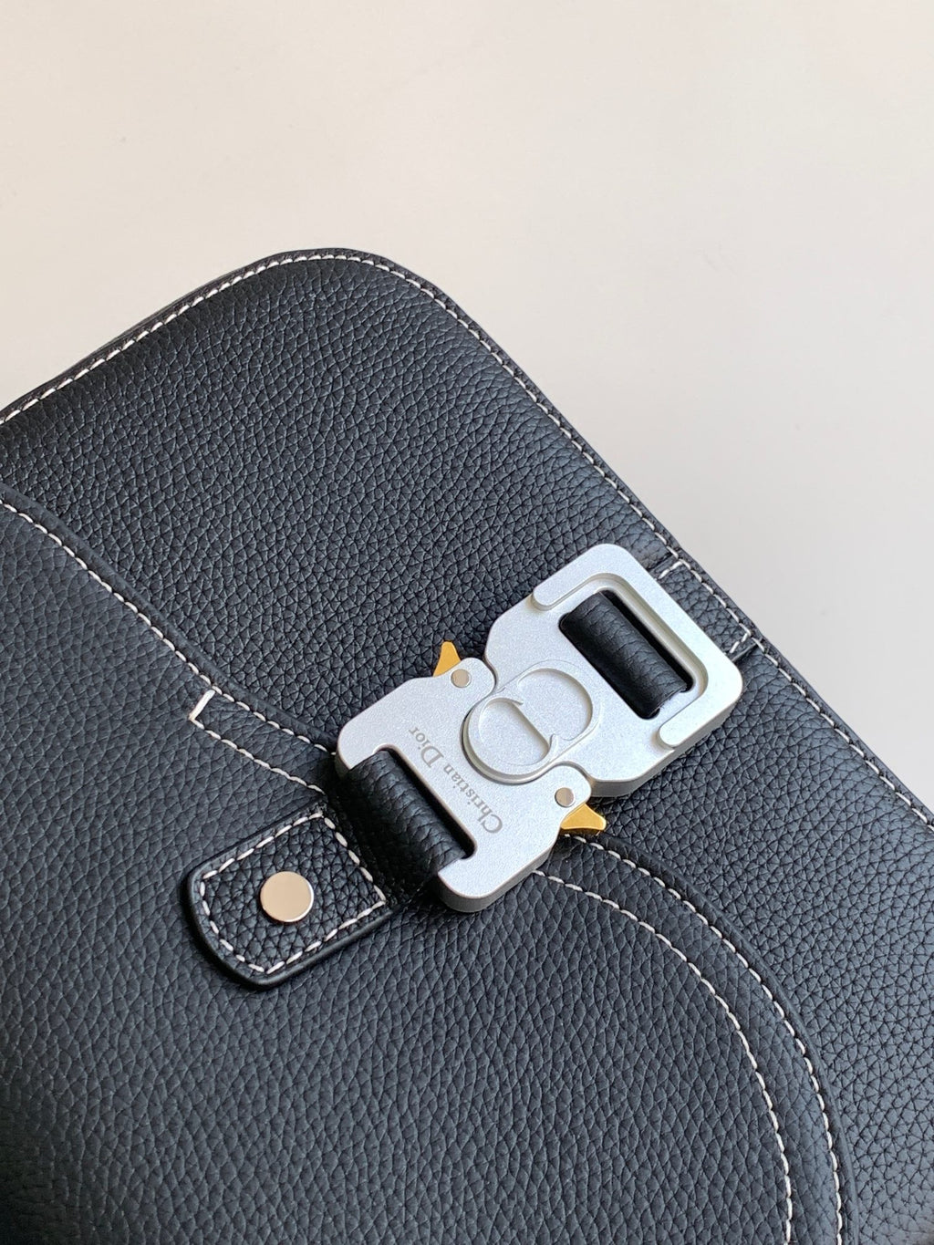 Dark textured leather bag close-up with silver lock clasp and stitched trim