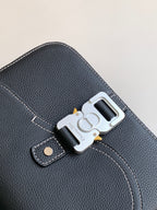 Dark textured leather bag close-up with silver lock clasp and stitched trim