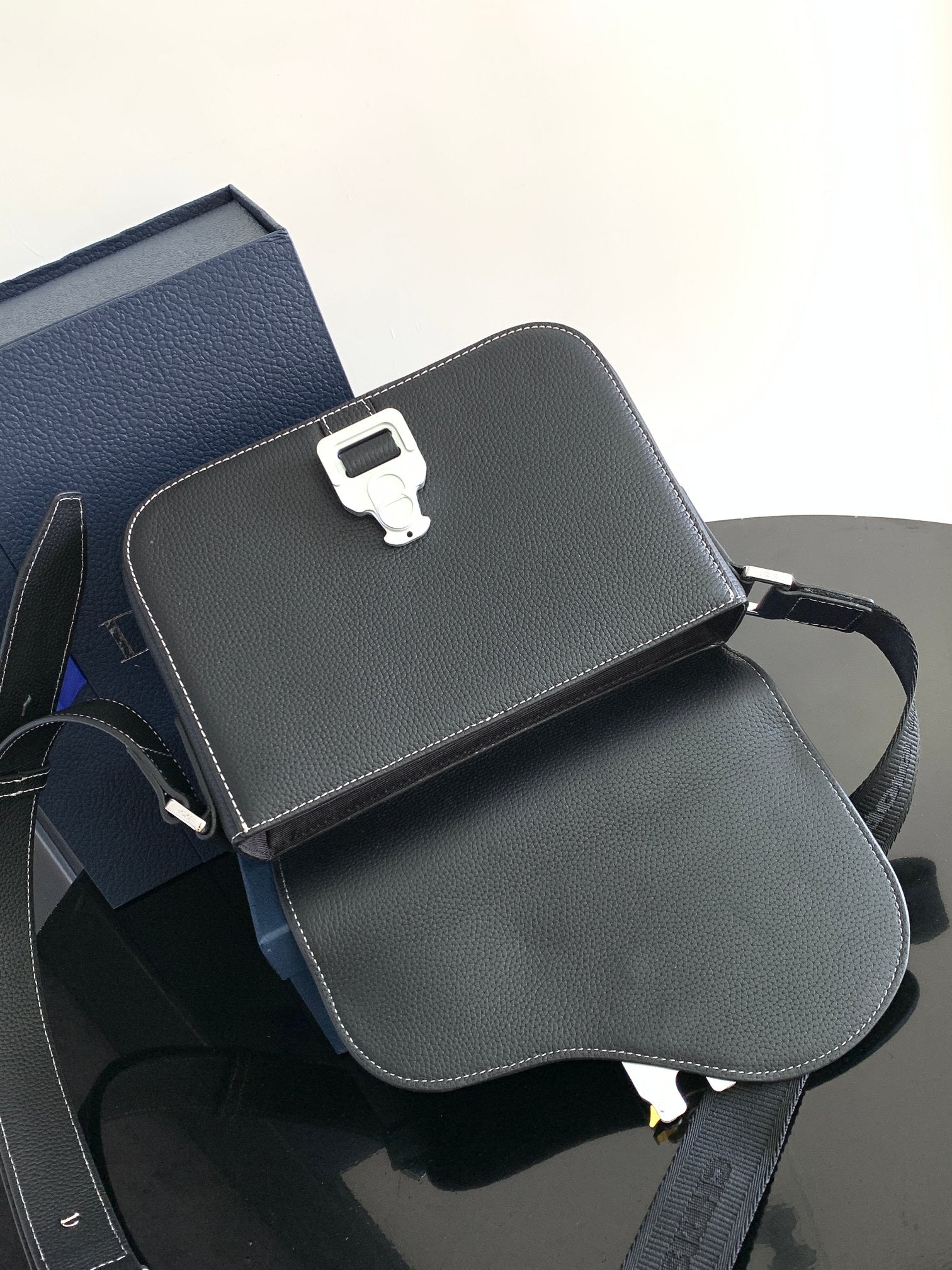 Dark textured leather crossbody bag with flap, adjustable strap, and metal clasp