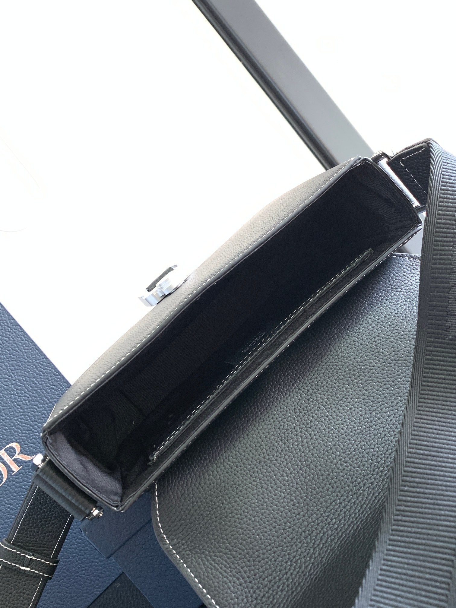 Dark textured leather shoulder bag interior with top flap and metal hardware