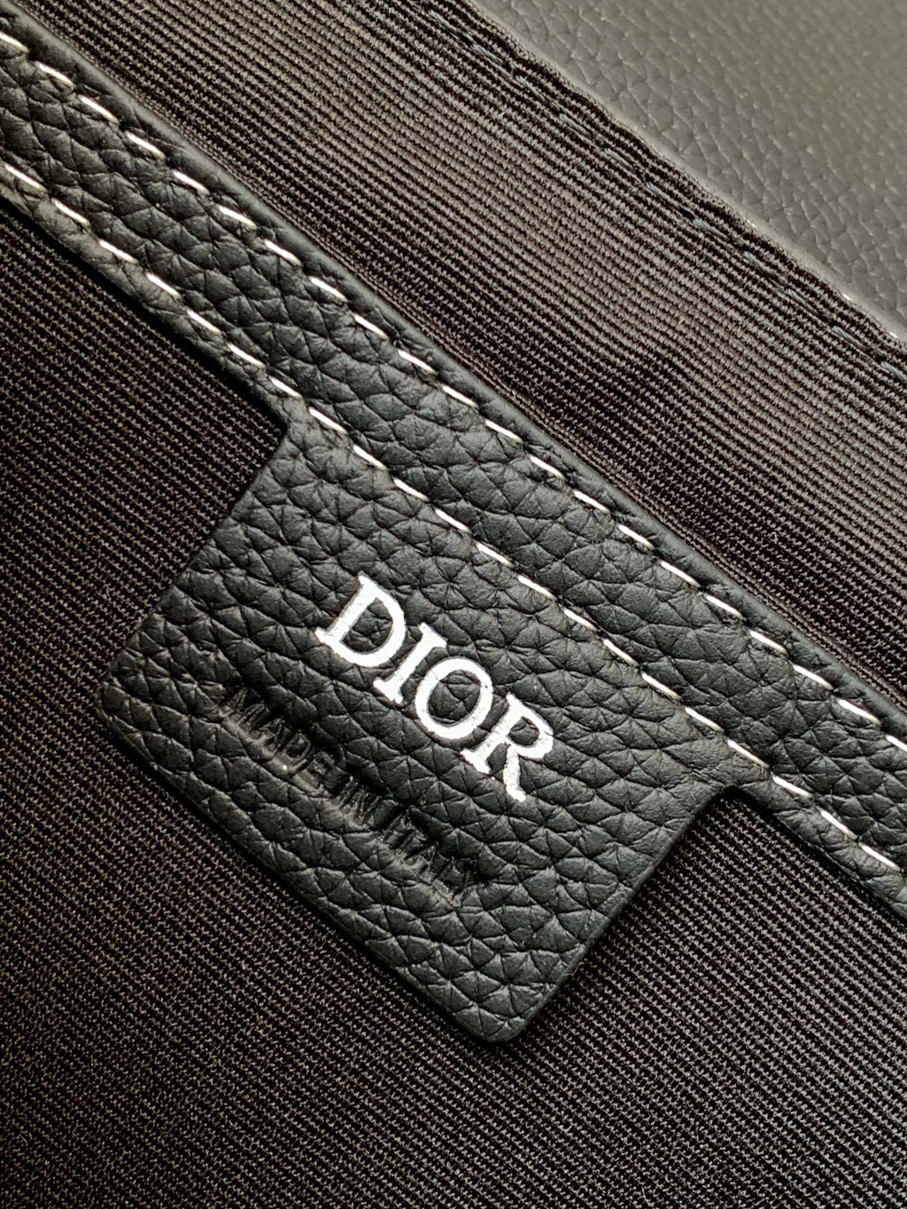 Dark leather bag interior label with Dior logo patch and stitched pocket