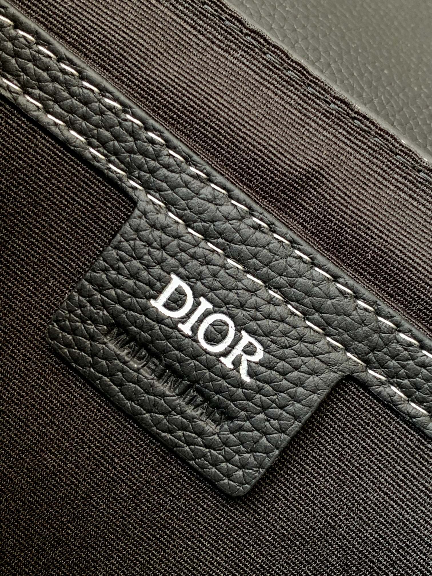 Dark leather bag interior label with Dior logo patch and stitched pocket