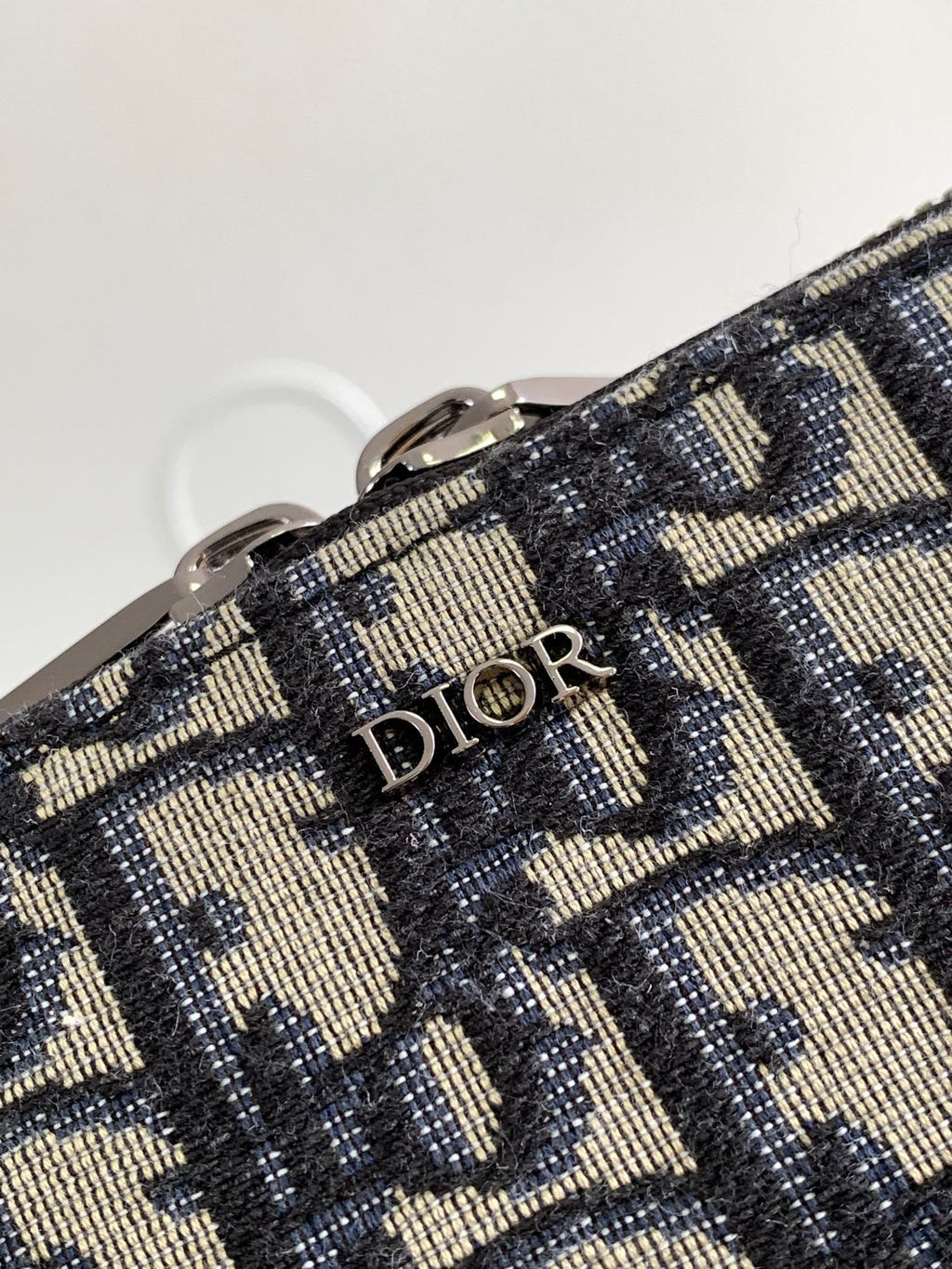 Dior pattern bag fabric close-up with “Dior” lettering on woven navy and beige material
